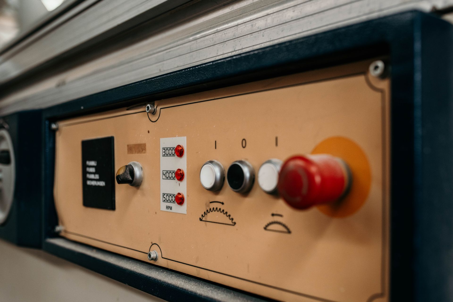 Pannello di controllo con pulsanti, interruttori e un pulsante di arresto di emergenza.