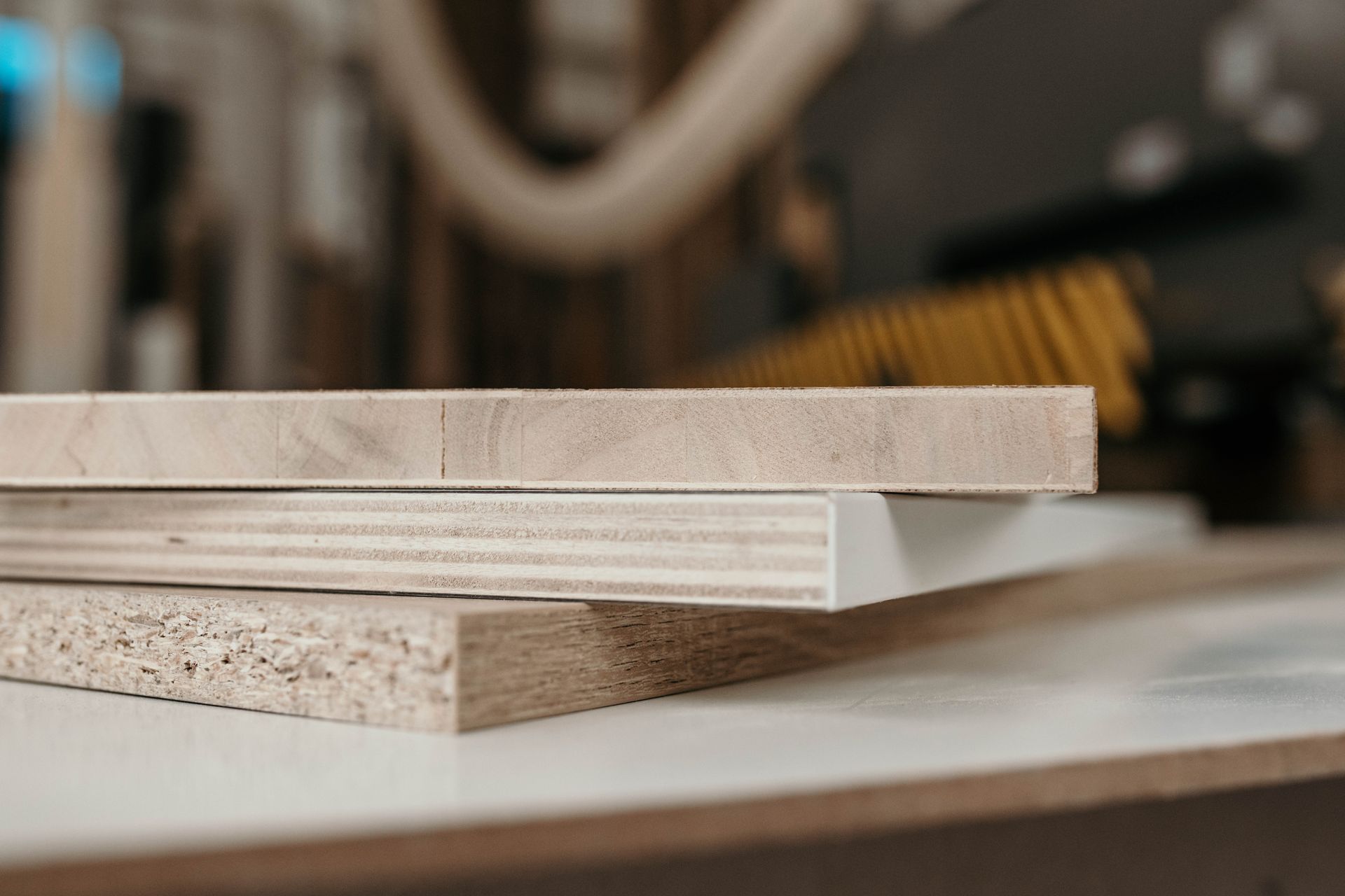 Tre pannelli di legno impilati: truciolato, compensato e legno massello.