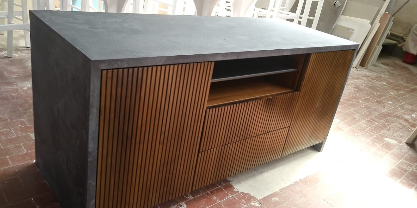 Mobile in legno con ante scanalate, piano di lavoro scuro e ripiano aperto.