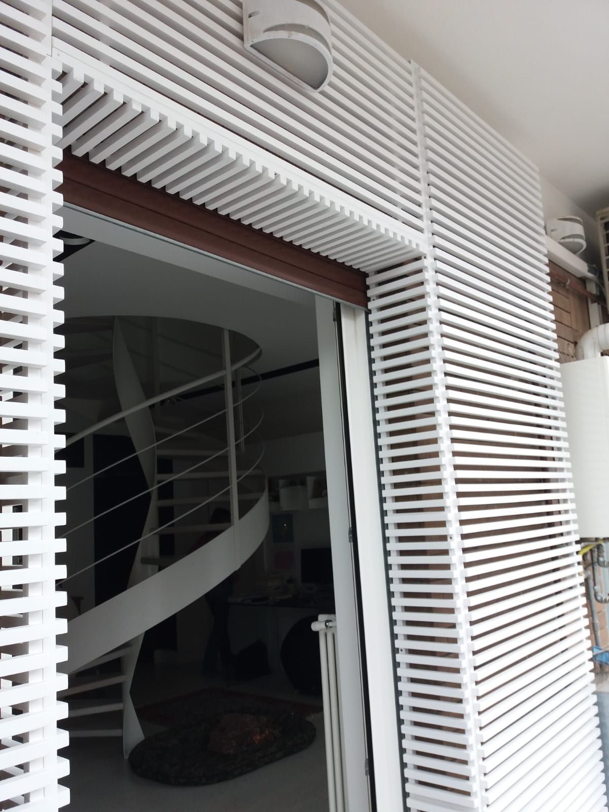 La facciata bianca a listelli circonda un portale che rivela una scala a chiocciola all'interno.