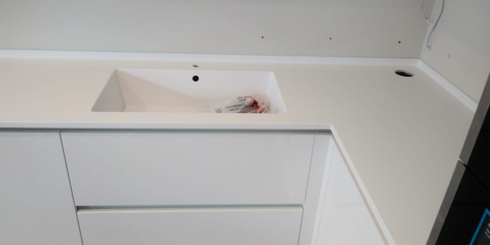 Piano di lavoro bianco della cucina con lavello incorporato e mobili bianchi.