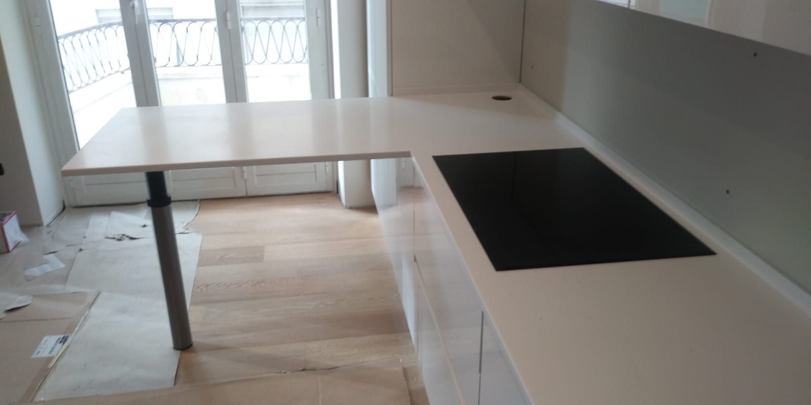 Bancone da cucina bianco con piano cottura nero, un piccolo bancone per la colazione e una finestra.