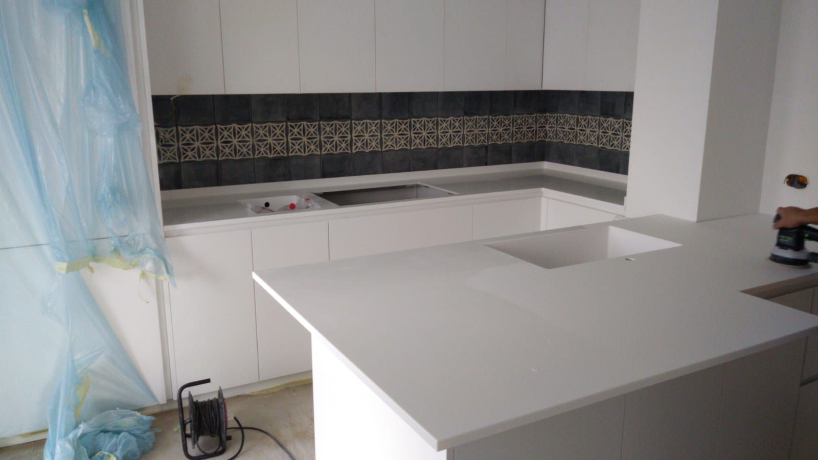 Moderna cucina bianca con ripiani bianchi, paraschizzi scuro e isola.