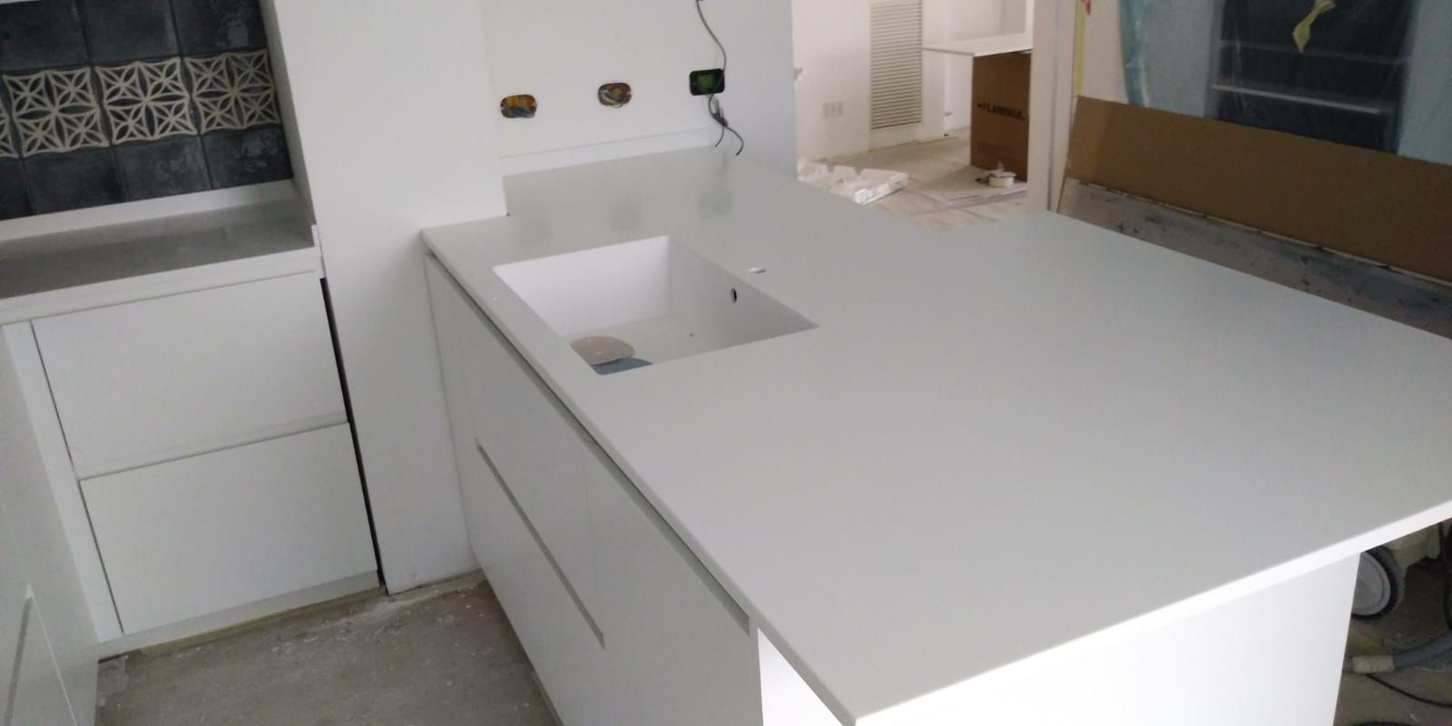 Cucina bianca con piano di lavoro e lavello integrato. Mobili bianchi. Lavori in corso.