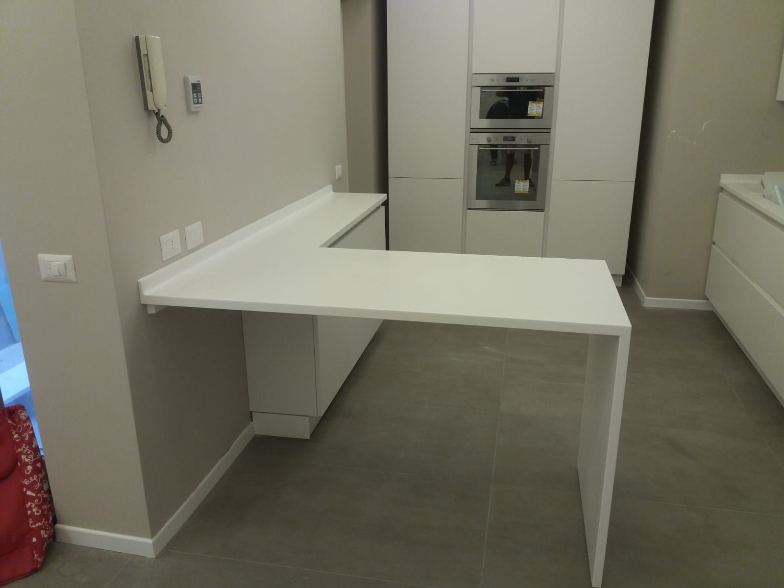 Un bancone da cucina bianco a forma di L con gamba di supporto, in un ambiente cucina moderno.