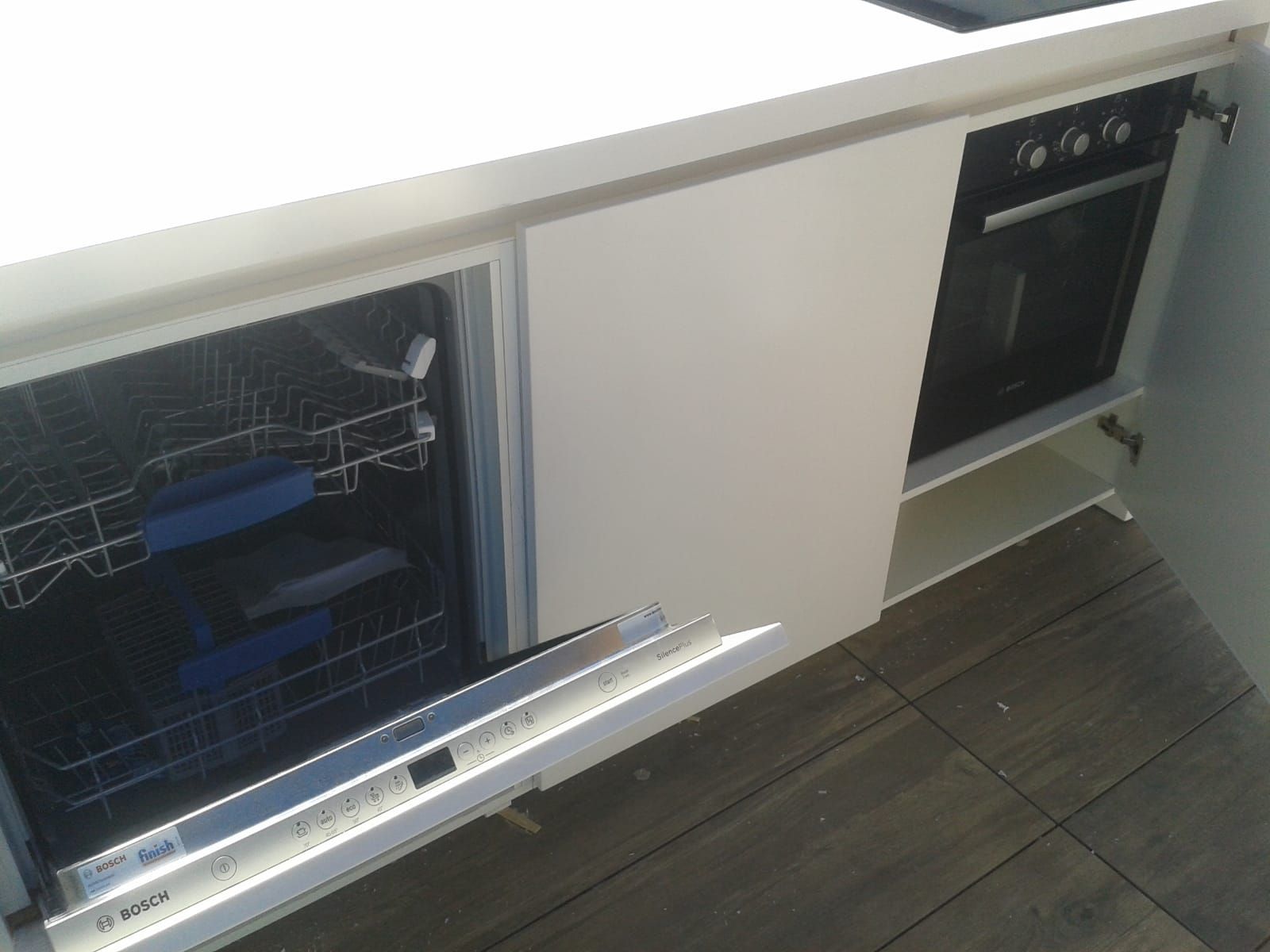 Mobili da cucina bianchi con lavastoviglie e forno a vista.