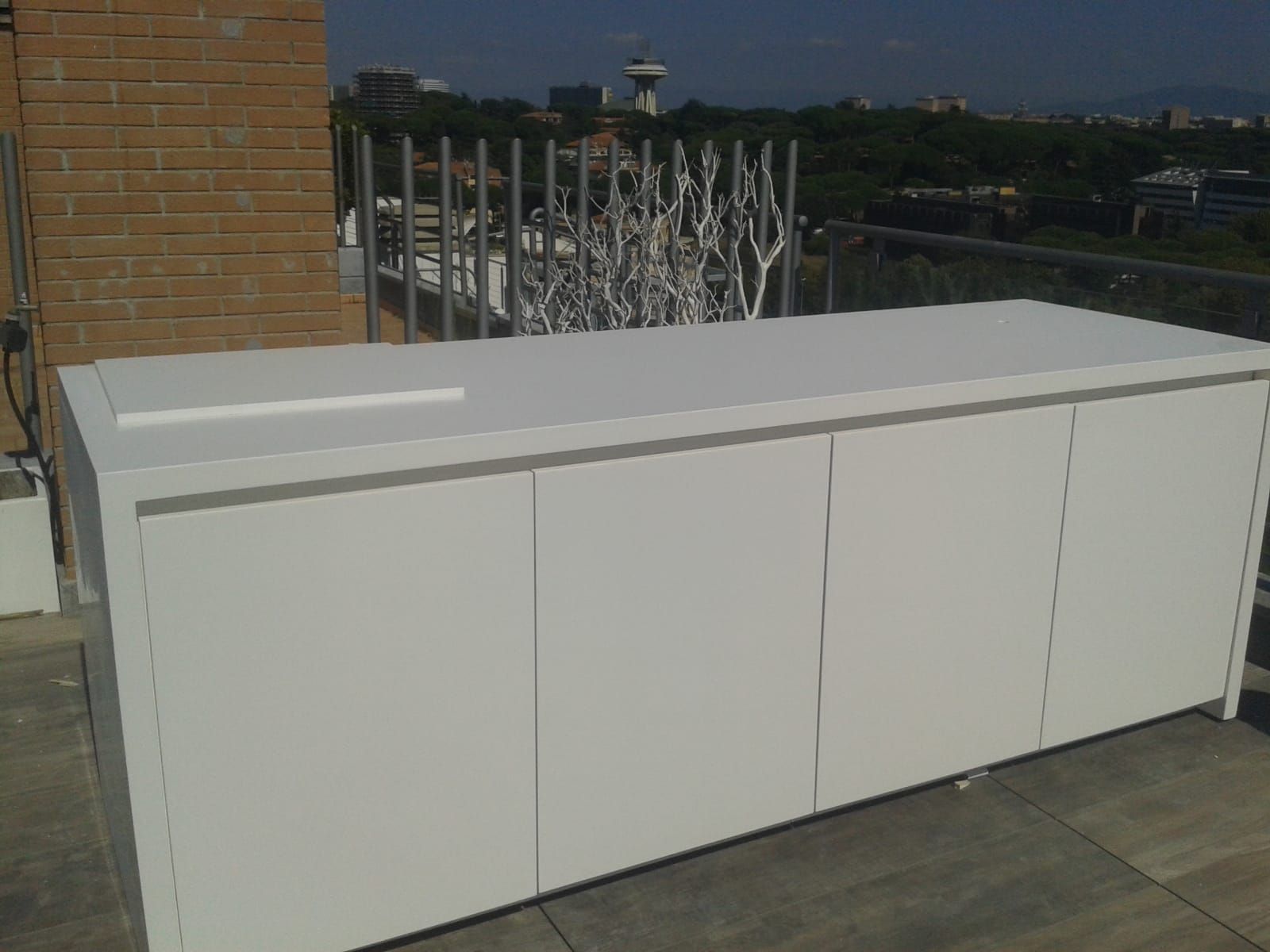 Mobiletto bianco per riporre gli oggetti all'aperto, su un tetto con vista sulla città.