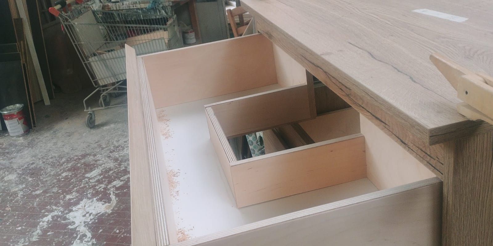 Un progetto di falegnameria in corso. Un mobiletto di colore chiaro ha cassetti aperti, con all'interno piccoli scomparti.