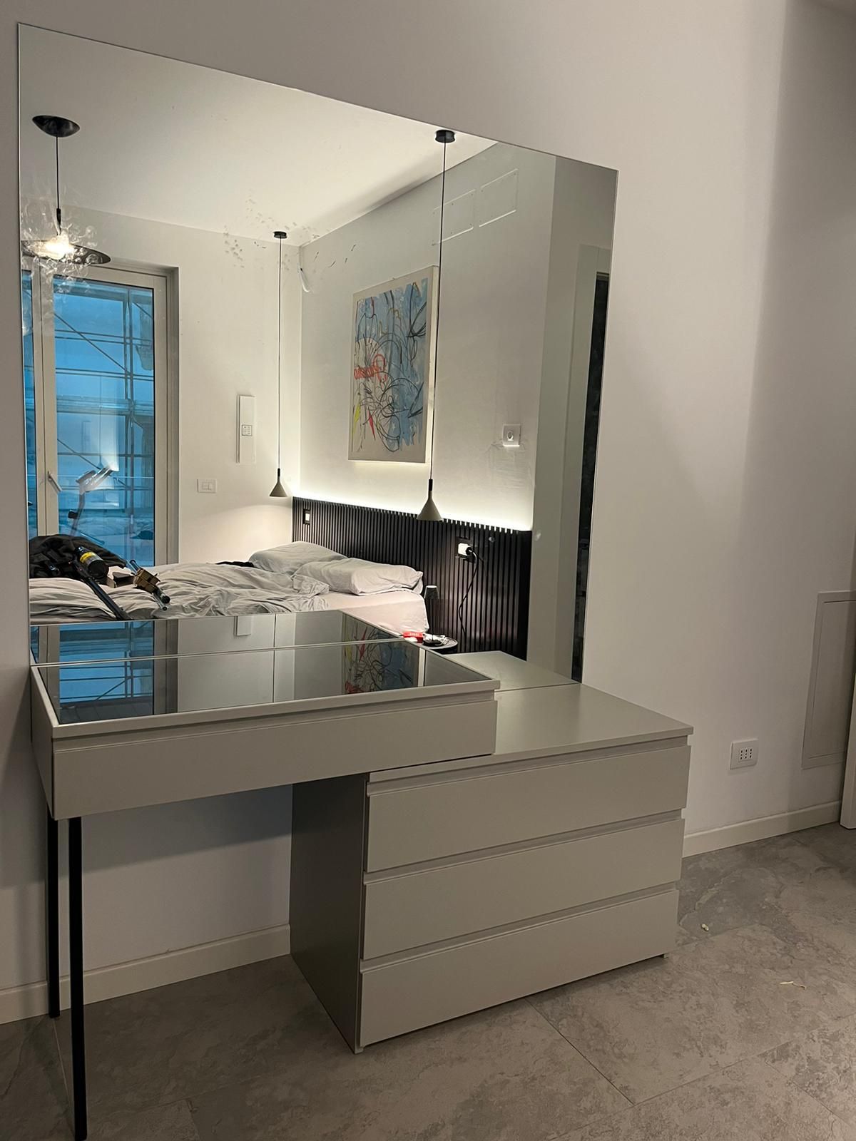 Mobiletto con specchio, cassetti grigio chiaro, gambe nere, piano in vetro riflettente, sfondo per la camera da letto.