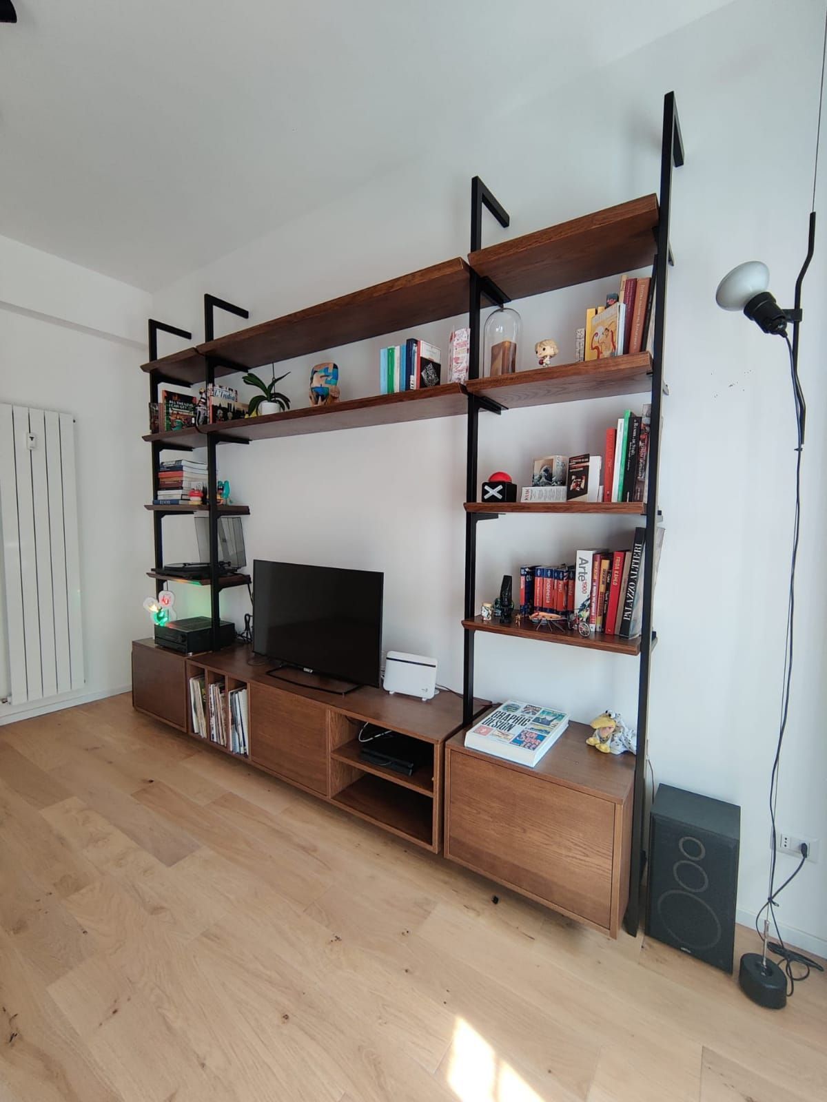 Scaffale in legno e metallo nero con TV, libri e decorazioni.