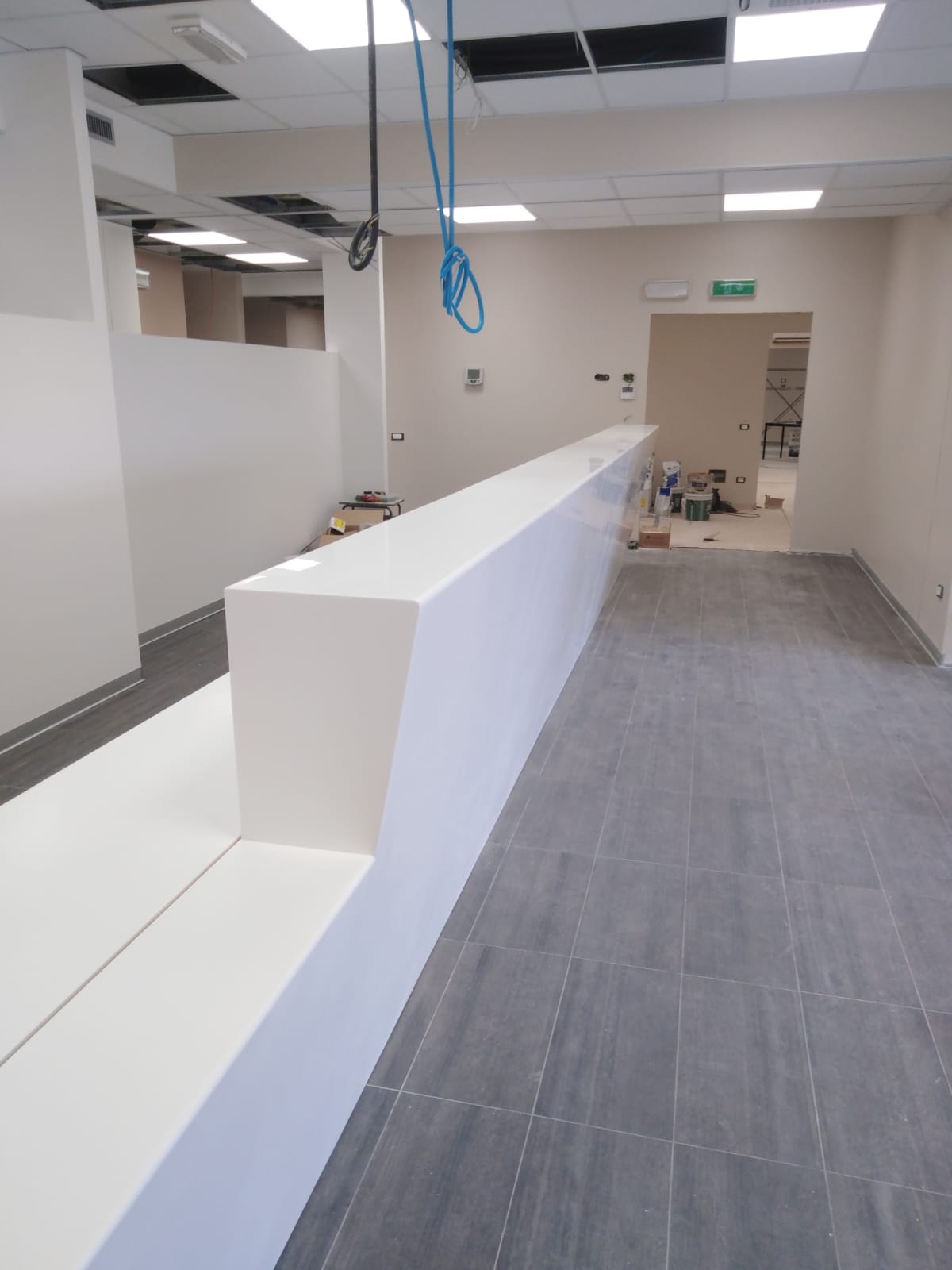 Bancone della reception bianco in un nuovo spazio ufficio vuoto con pavimento piastrellato grigio.