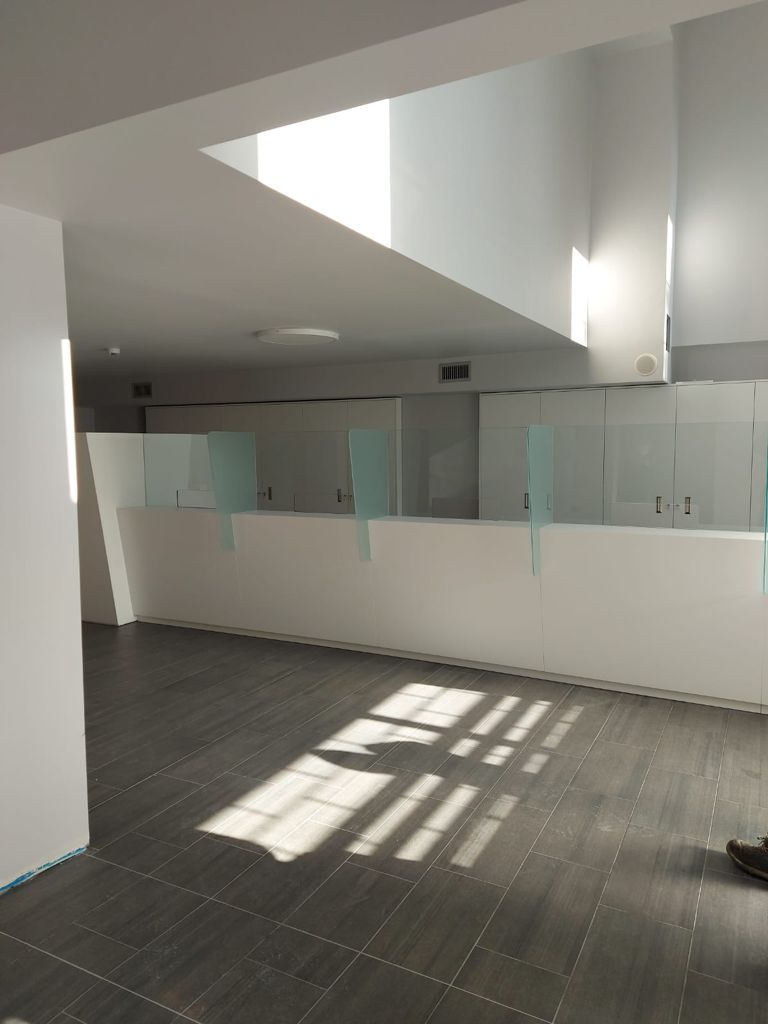 Sportelli vuoti, lucernari sopraelevati illuminano il pavimento piastrellato grigio.