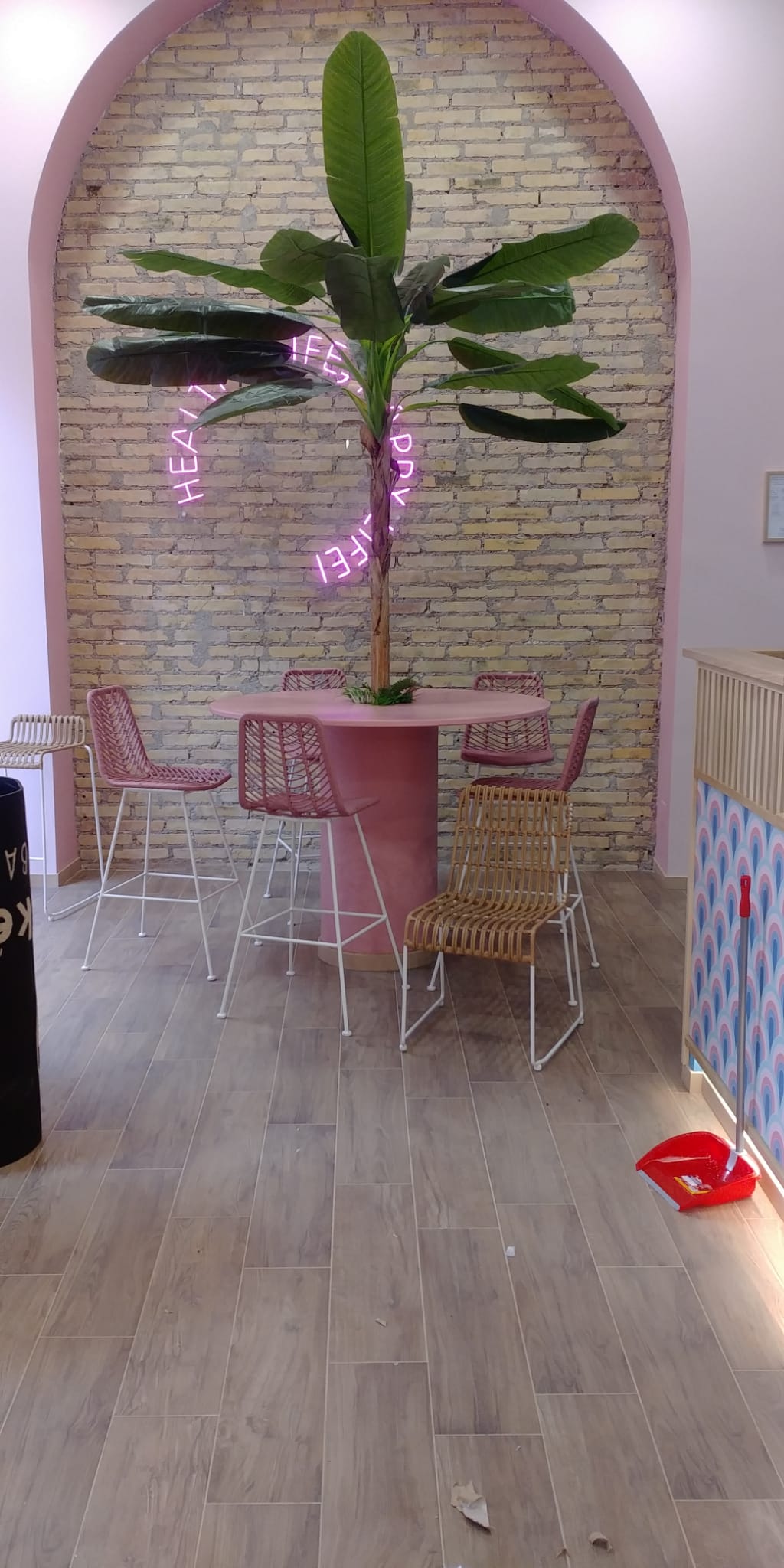 Interno di un bar rosa con un finto banano, un tavolino e sedie.