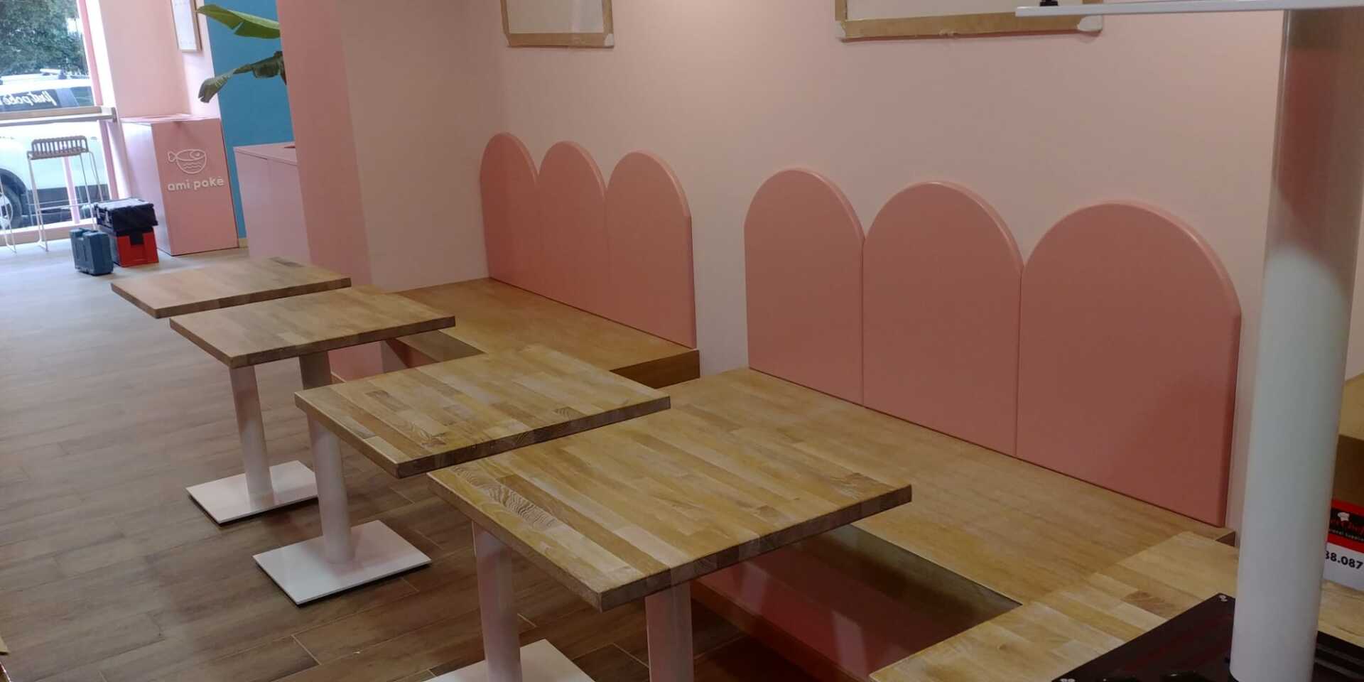 L'interno di un bar con pareti rosa, tavoli in legno e posti a sedere.