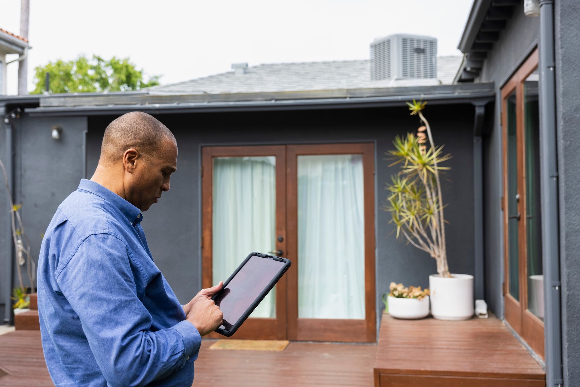 A mature male real estate agent using a digital tablet while standing in front of a house