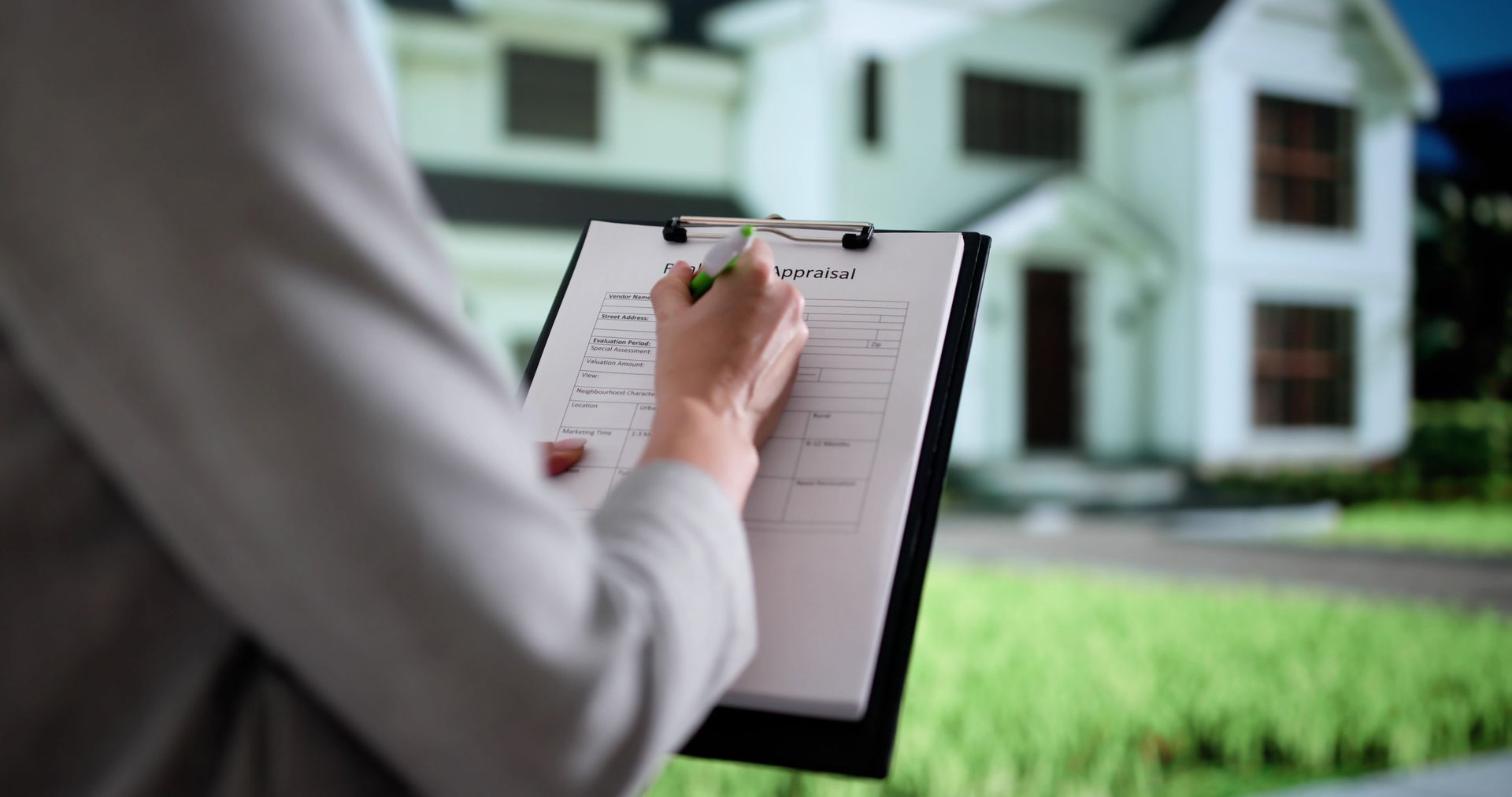 Person writing on an appraisal clipboard with a house in the background. Person writing on an appraisal clipboard with a house in the background.