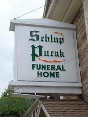 A sign for a funeral home is hanging from the side of a building.