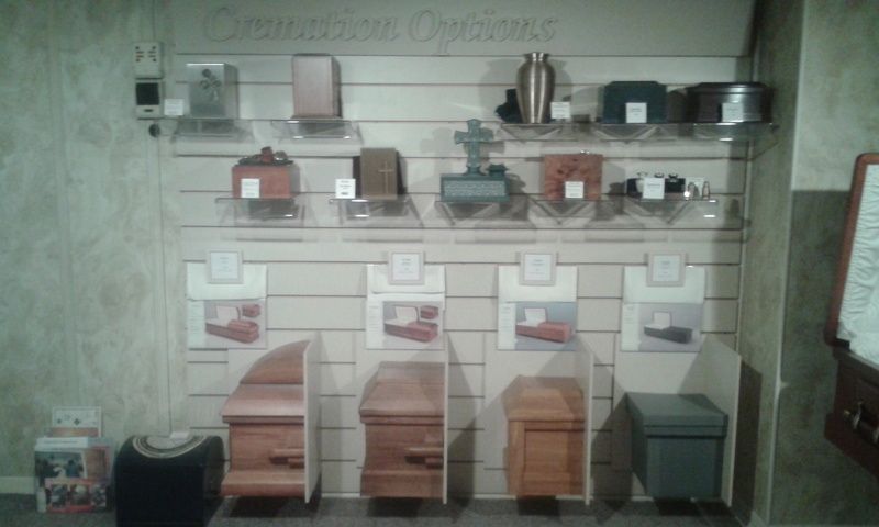 There are many different types of coffins on display on the wall.