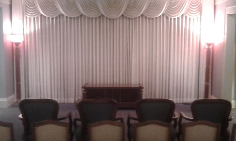 A row of chairs are sitting in front of a white curtain in a room.