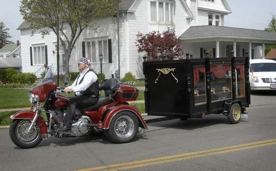A man is riding a motorcycle with a trailer attached to it.