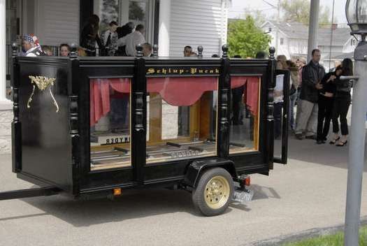 A black trailer with a red curtain is parked in front of a building.