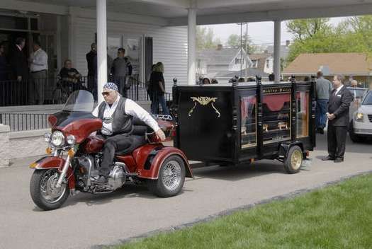 A man is riding a motorcycle with a trailer attached to it.