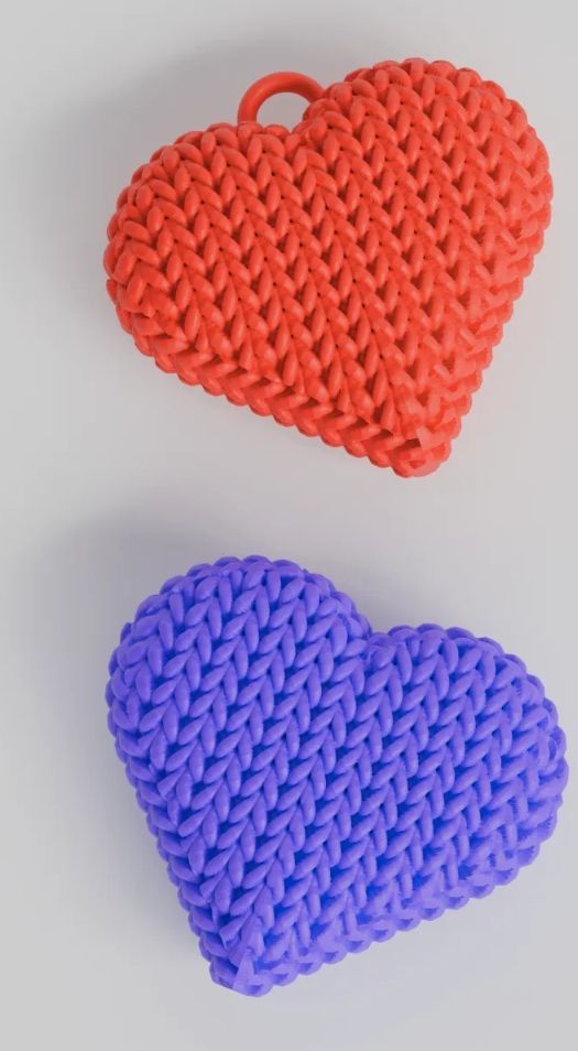 Rig-3d Twee hartvormige bedeltjes met een gebreide textuur, een oranje en een paarse, op een effen witte achtergrond.