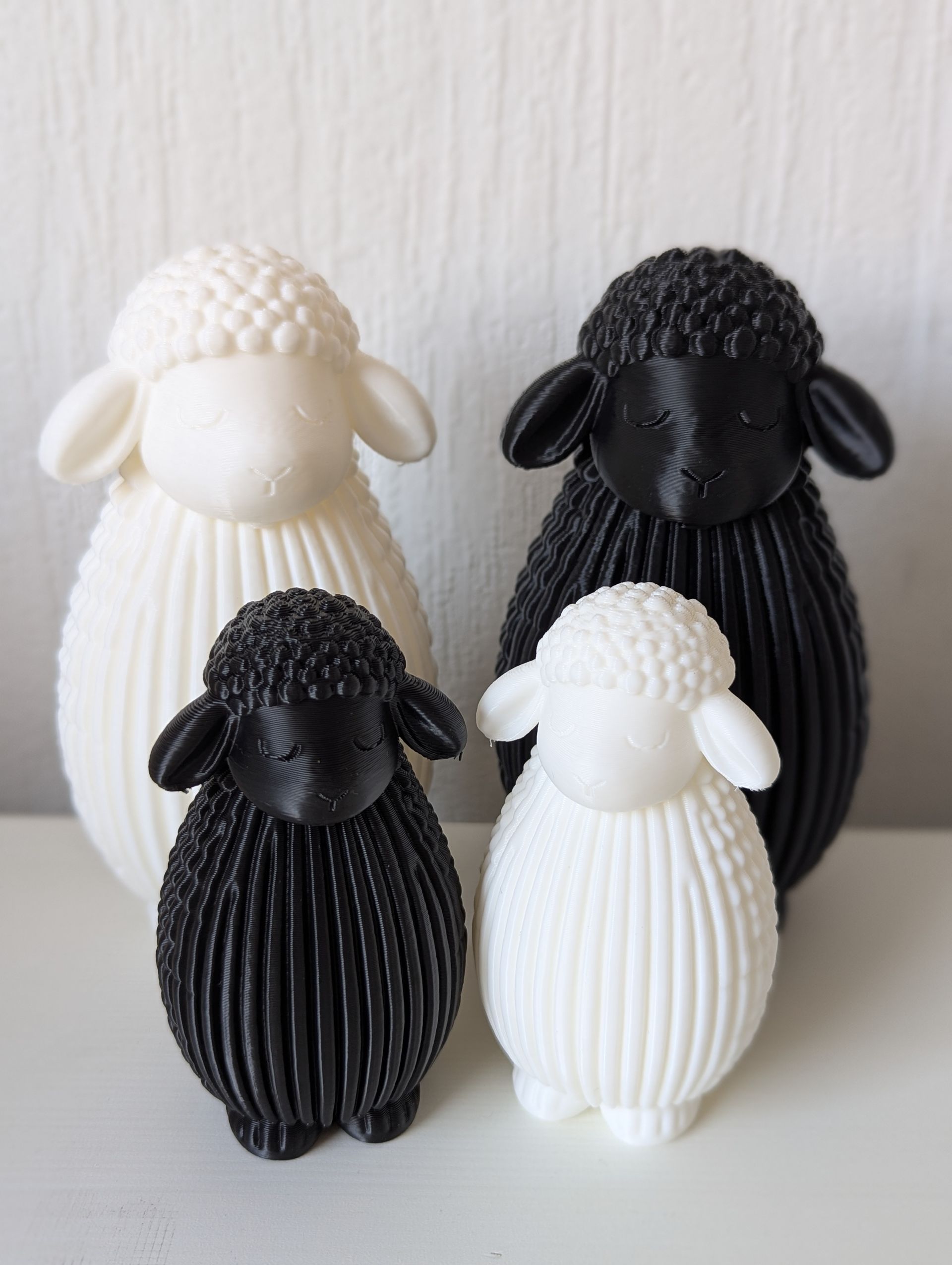 Rig-3d Op een witte ondergrond staan vier 3D-geprinte schaapjes, een groot en een klein schaap, beide in zwart en wit.