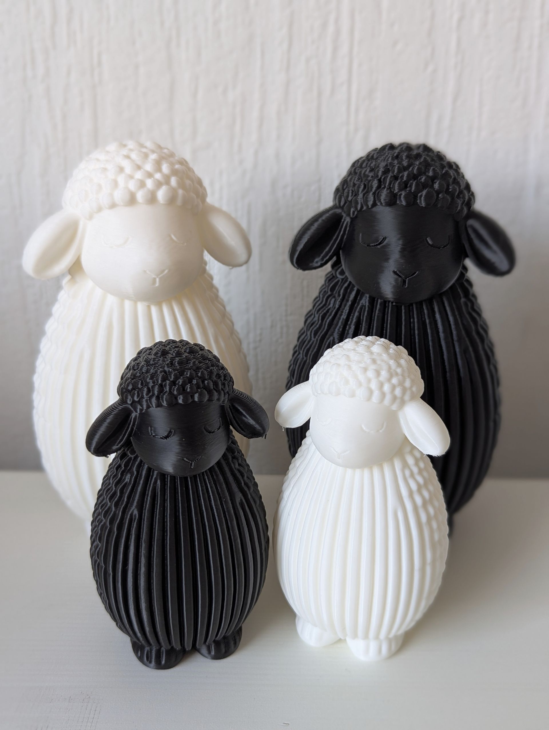 Rig-3d Op een witte ondergrond staan vier 3D-geprinte schaapjes, een groot en een klein schaap, beide in zwart en wit.