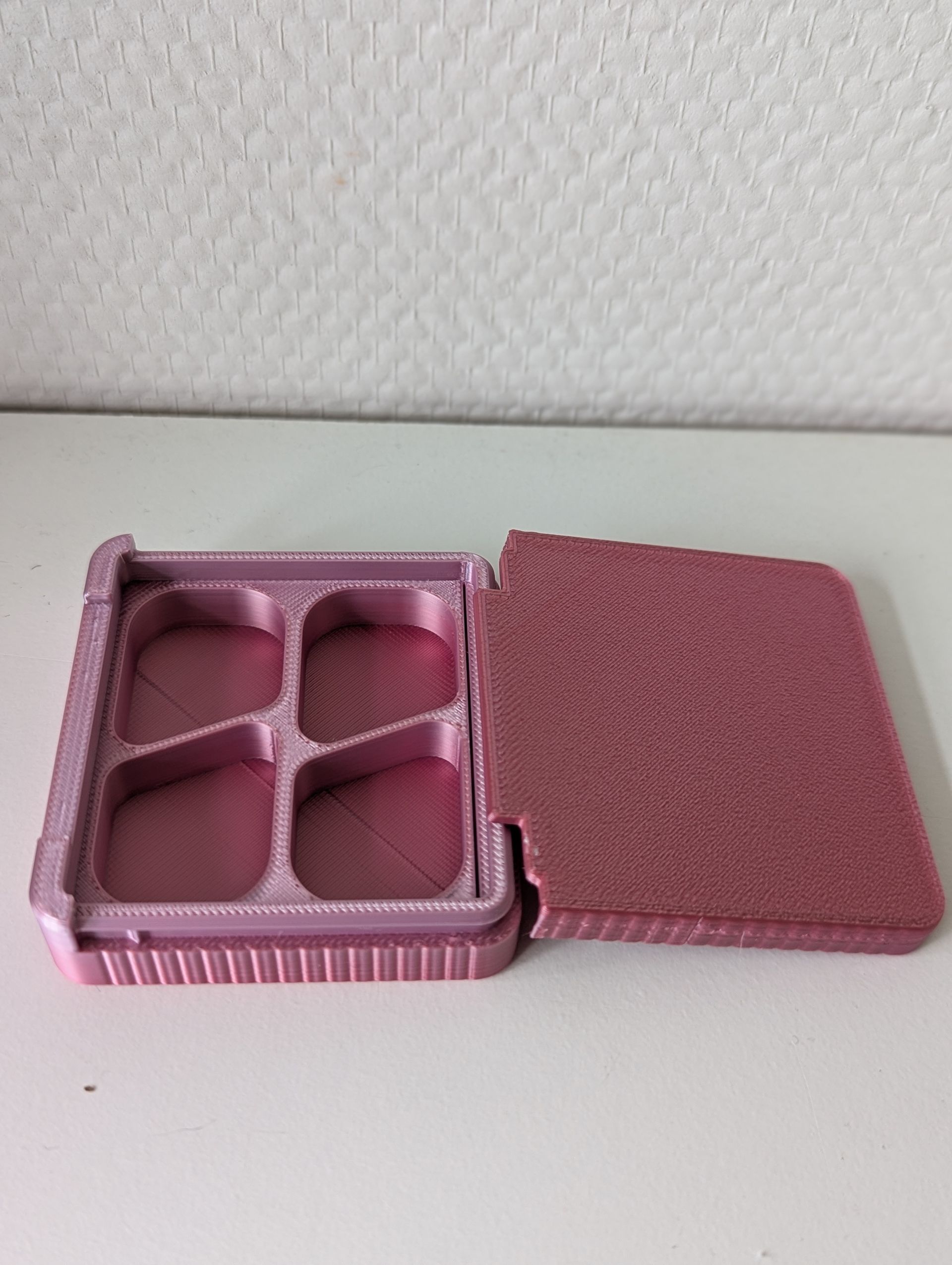 Rig-3d waterdrop Een grijze, vierkante 3D-geprinte doos met een gestructureerd bovenoppervlak, die op een vlakke witte ondergrond staat.