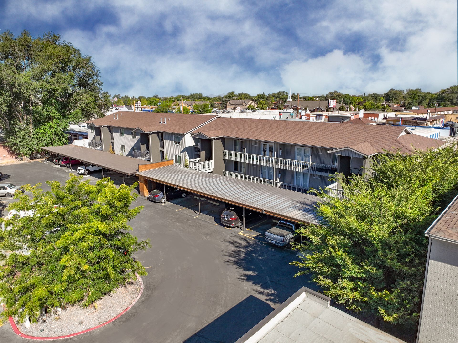 Aerial view of apartment complex with covered parking and landscaping.