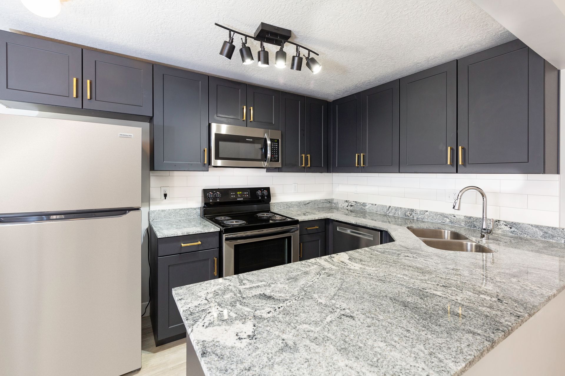 Kitchen with gray cabinets, stainless steel appliances, and granite countertops.