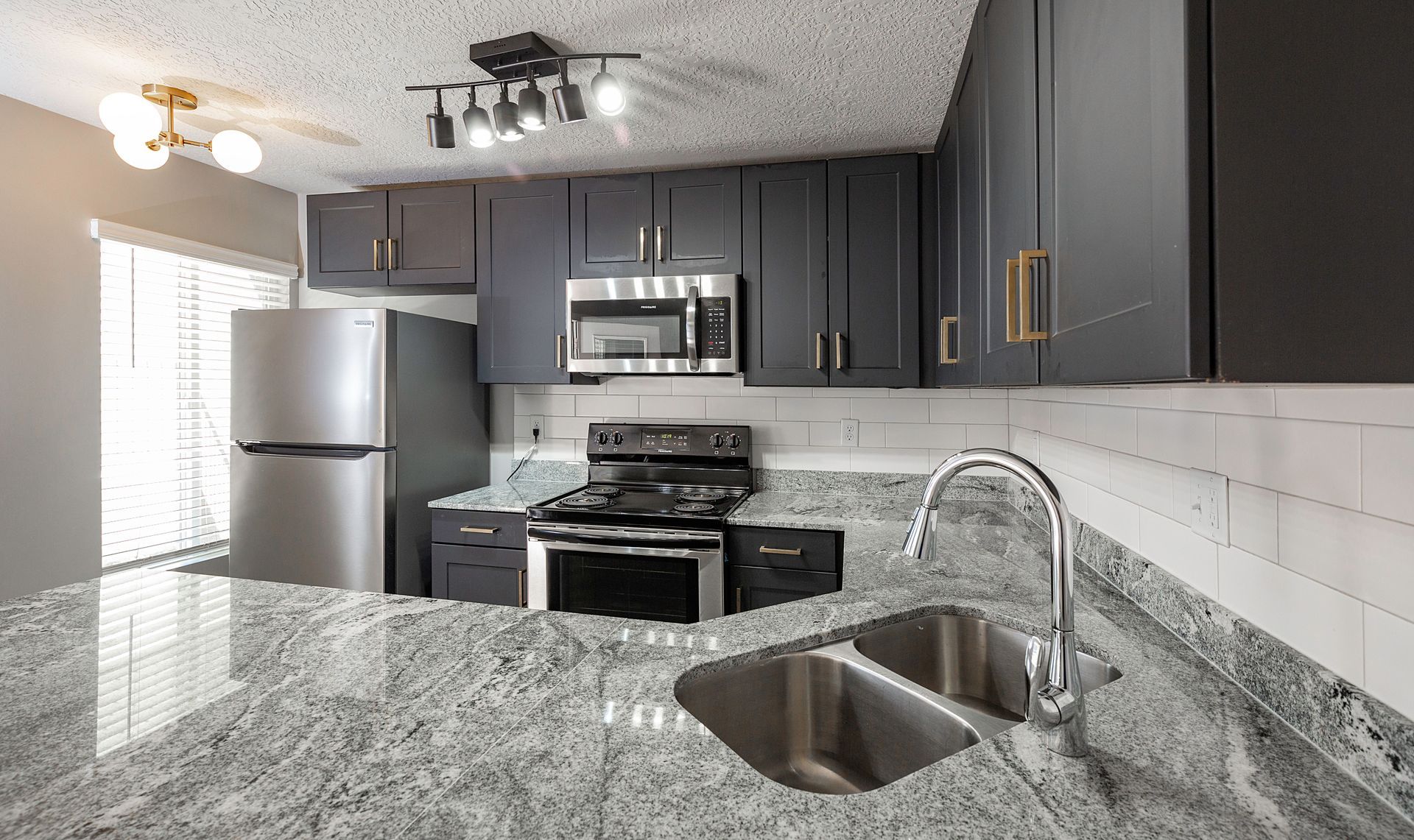 Kitchen with dark blue cabinets, stainless steel appliances, and a granite countertop.