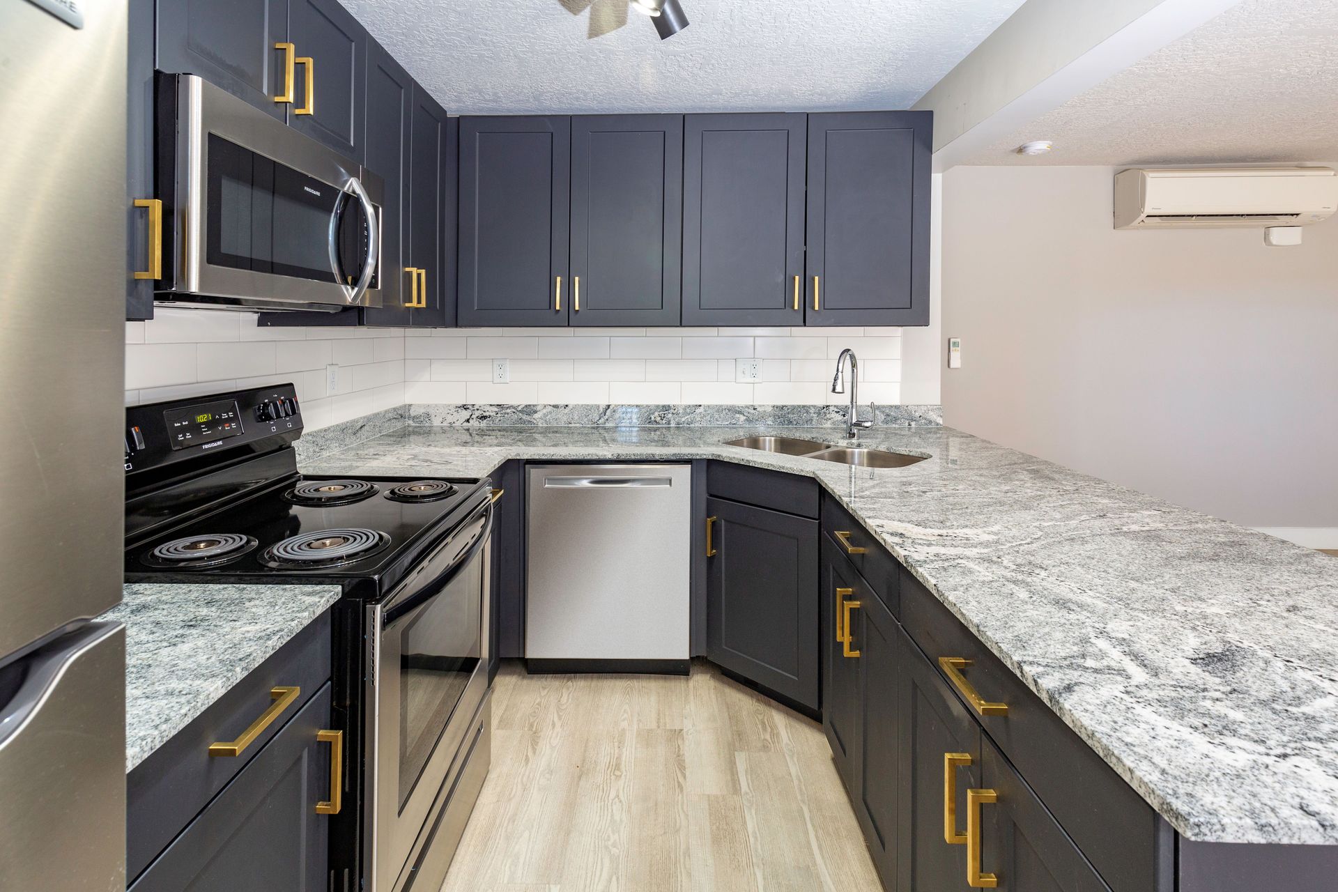 Modern kitchen with dark blue cabinets, stainless steel appliances, and granite countertops.