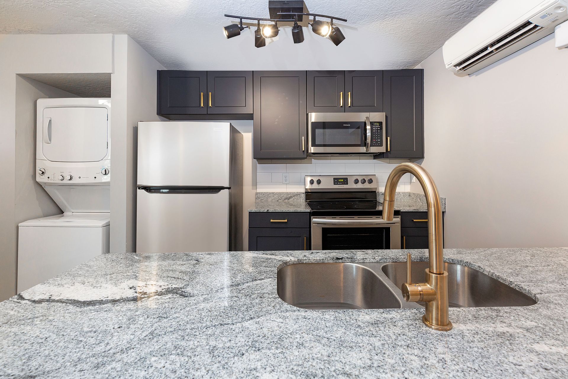 Modern kitchen with dark cabinets, stainless steel appliances, and granite countertops.