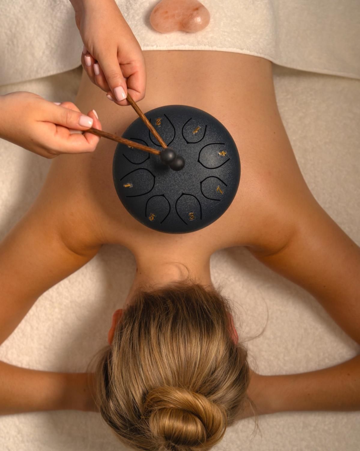 A woman is getting a massage with a drum on her back.