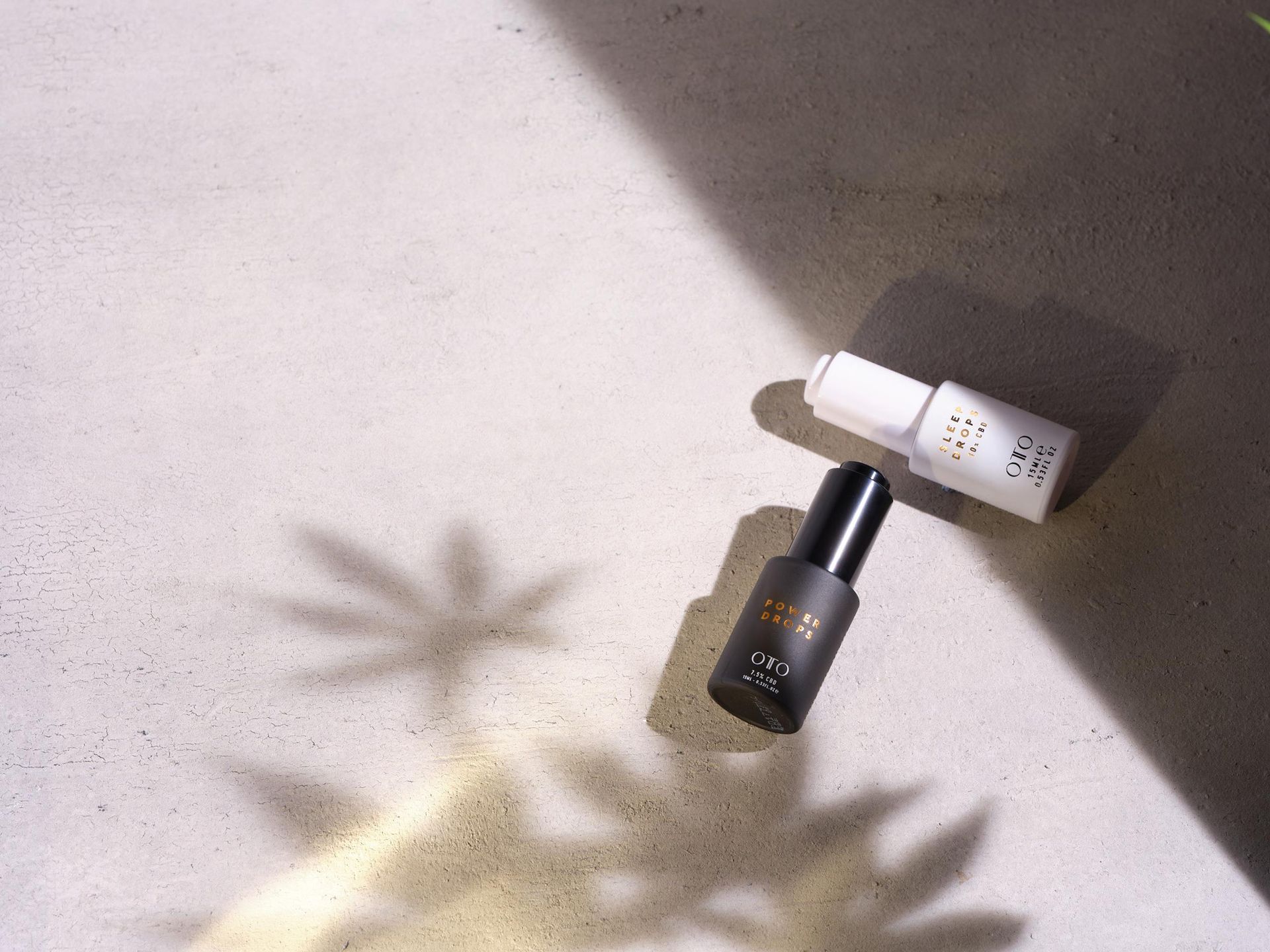 Two bottles of cosmetics are sitting on a table with their shadows cast on the wall.