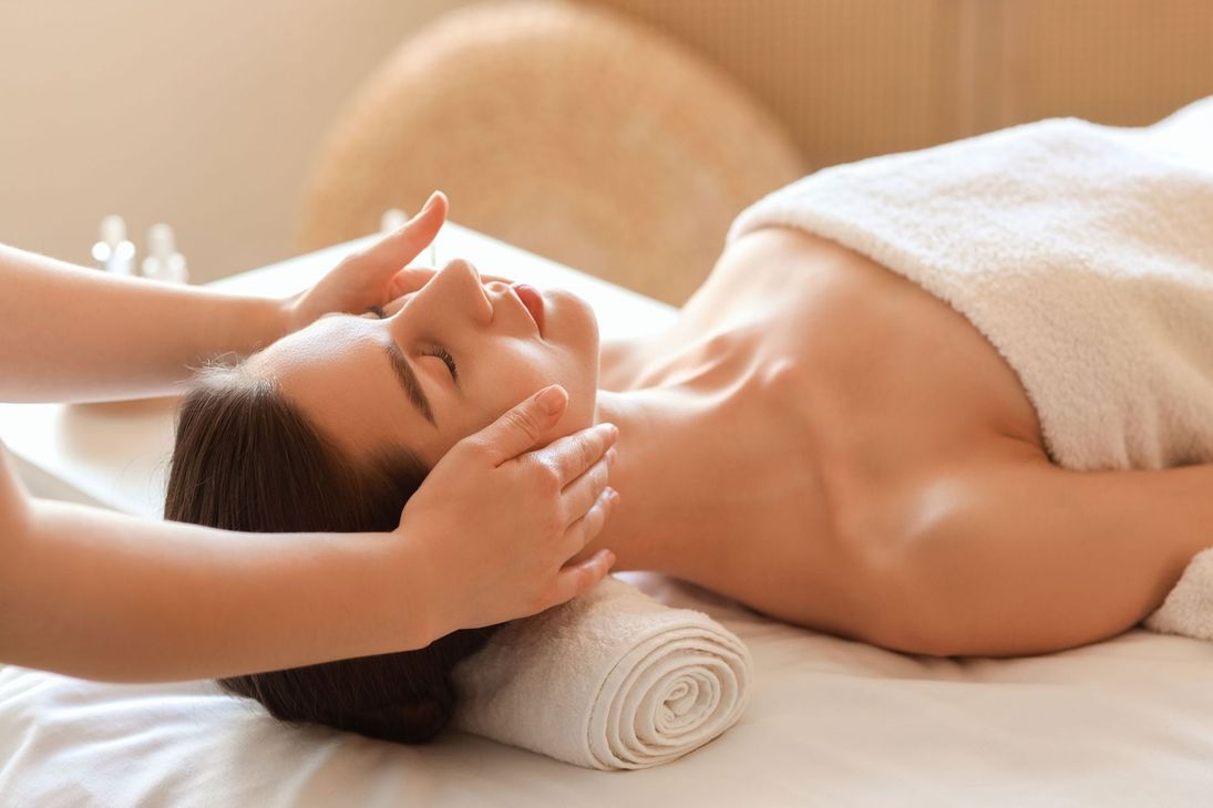 A woman is getting a facial massage at a spa.