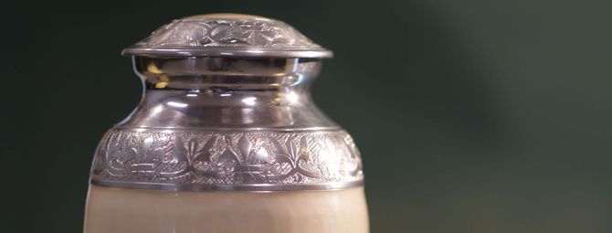 a silver urn filled with ashes is sitting on a table .