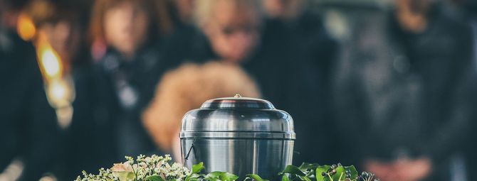 a close up of a silver urn and a funeral service in the background