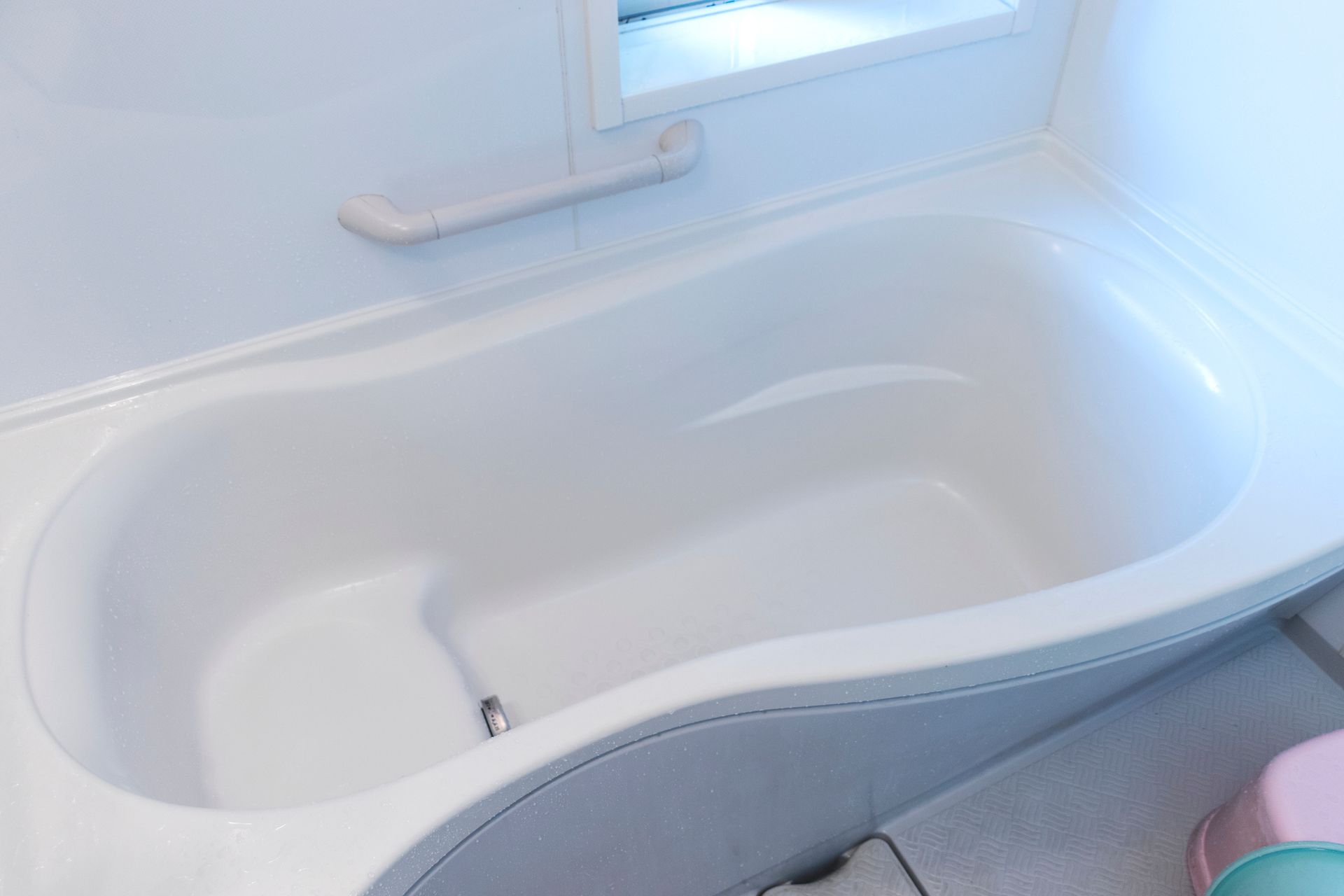 A white bathtub in a bathroom next to a window.