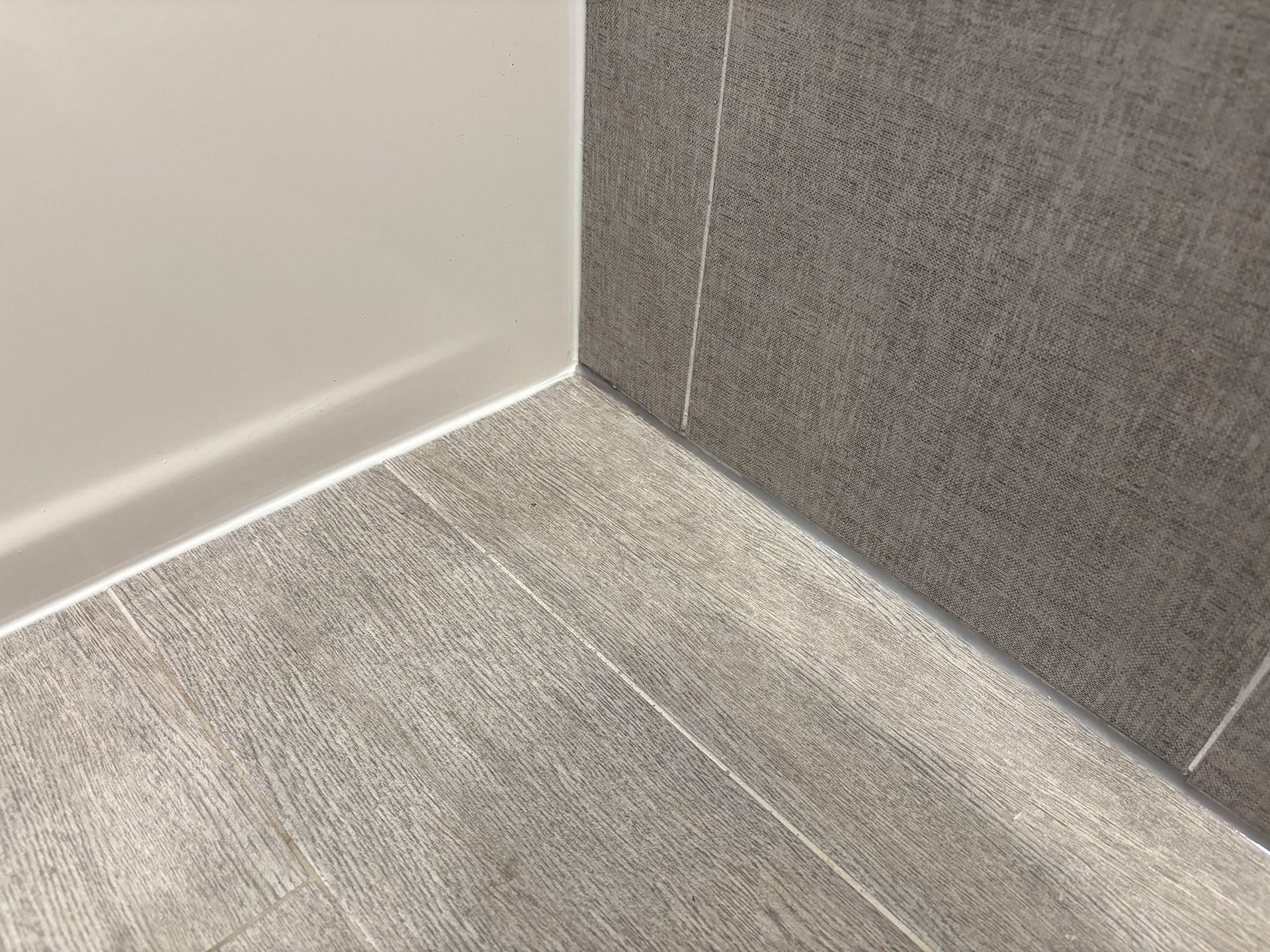 A close up of a tiled floor in a bathroom next to a wall.