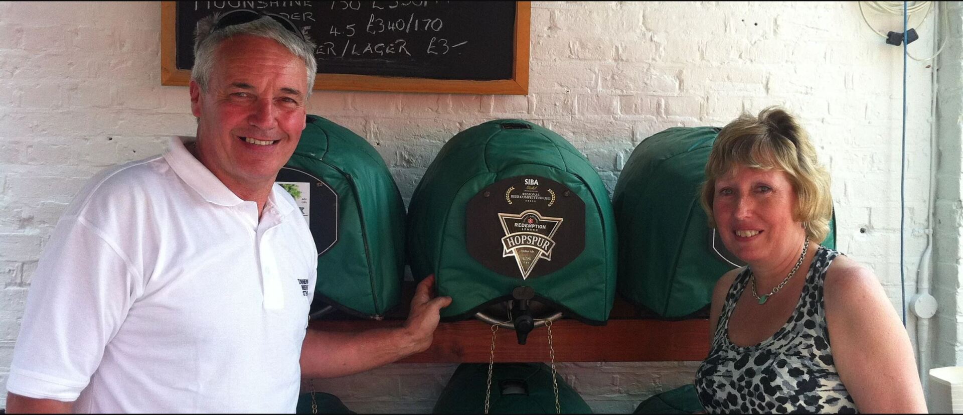 A man and a woman are standing in front of green barrels