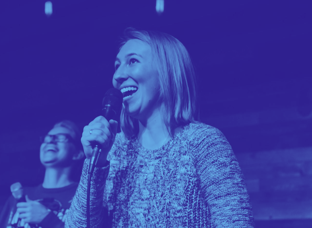 A woman is singing into a microphone on a stage.