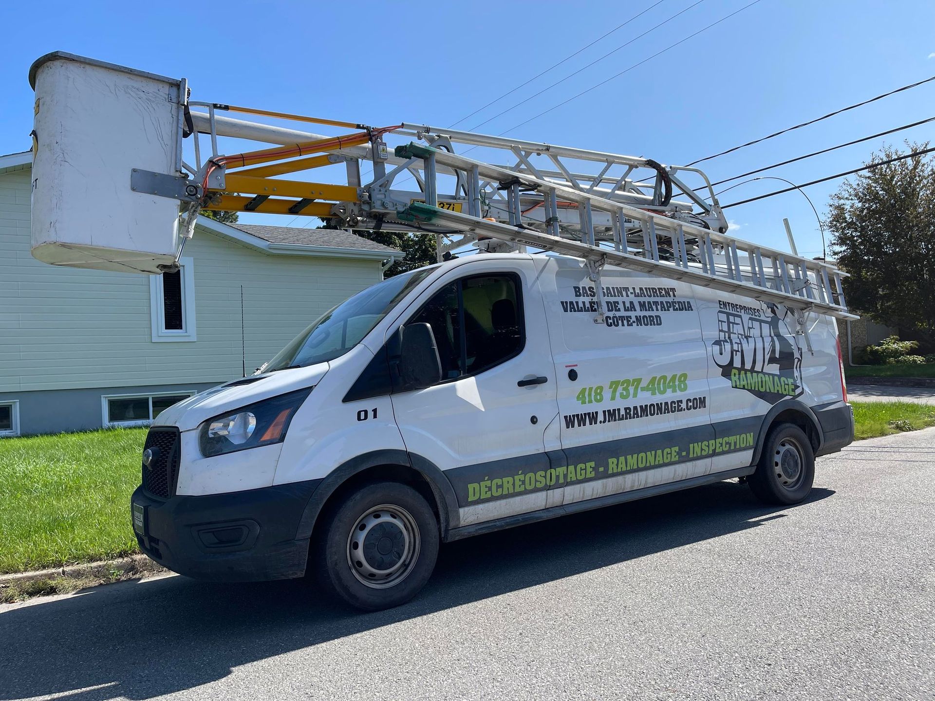 Une camionnette blanche surmontée d'une échelle est garée devant une maison.
