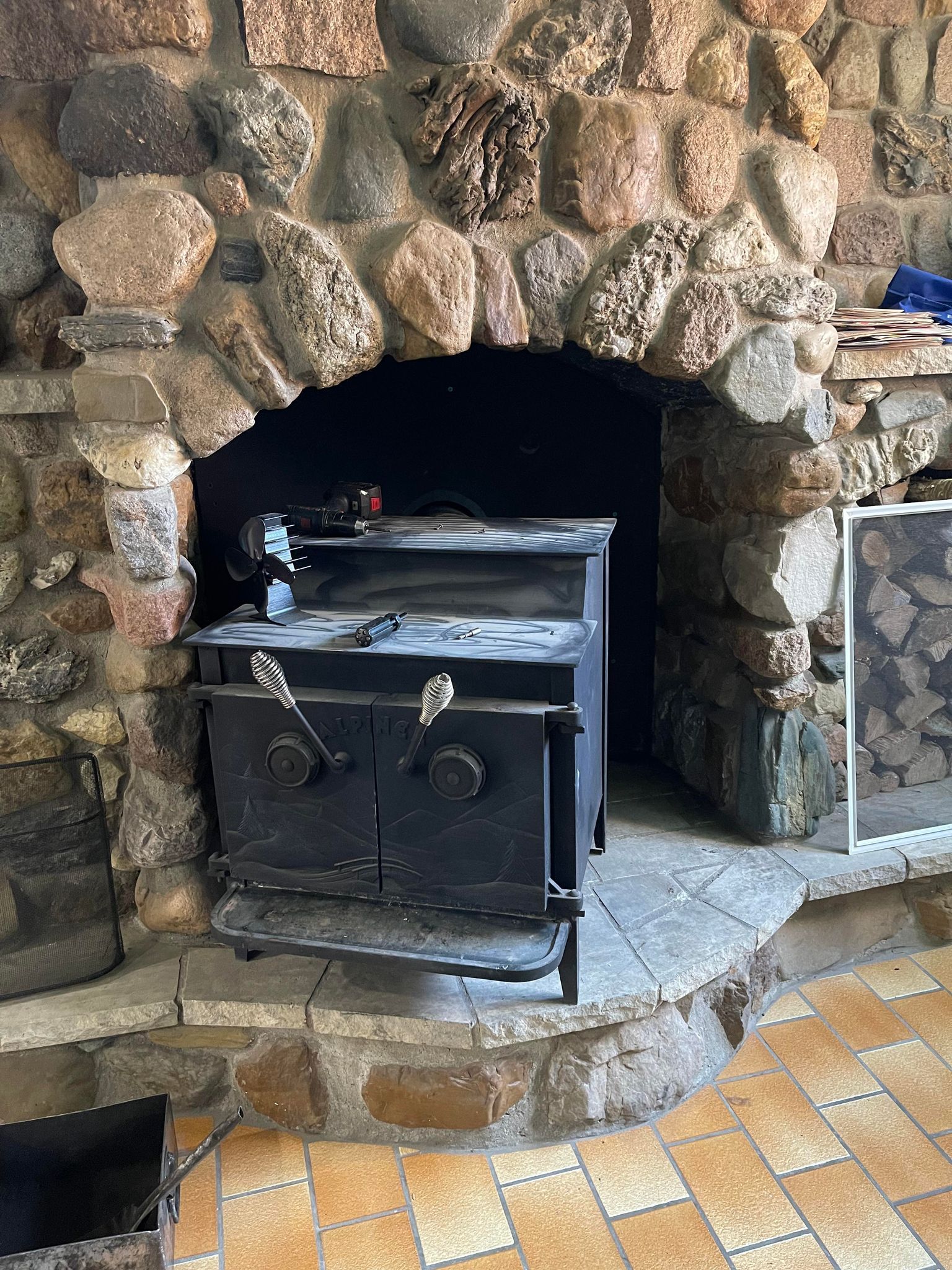 Un poêle à bois se trouve à l'intérieur d'une cheminée en pierre.