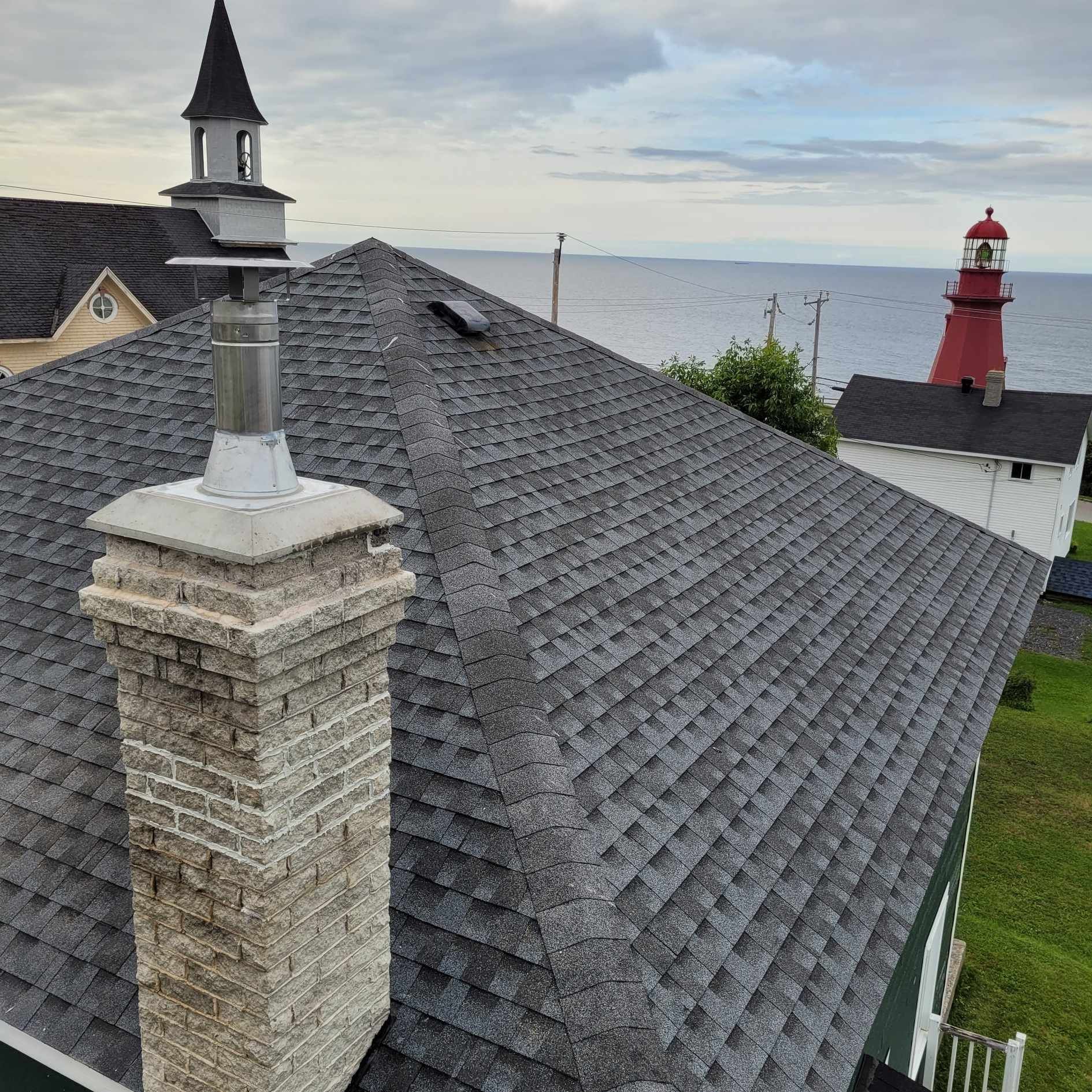 Un toit avec une cheminée et un phare en arrière-plan.