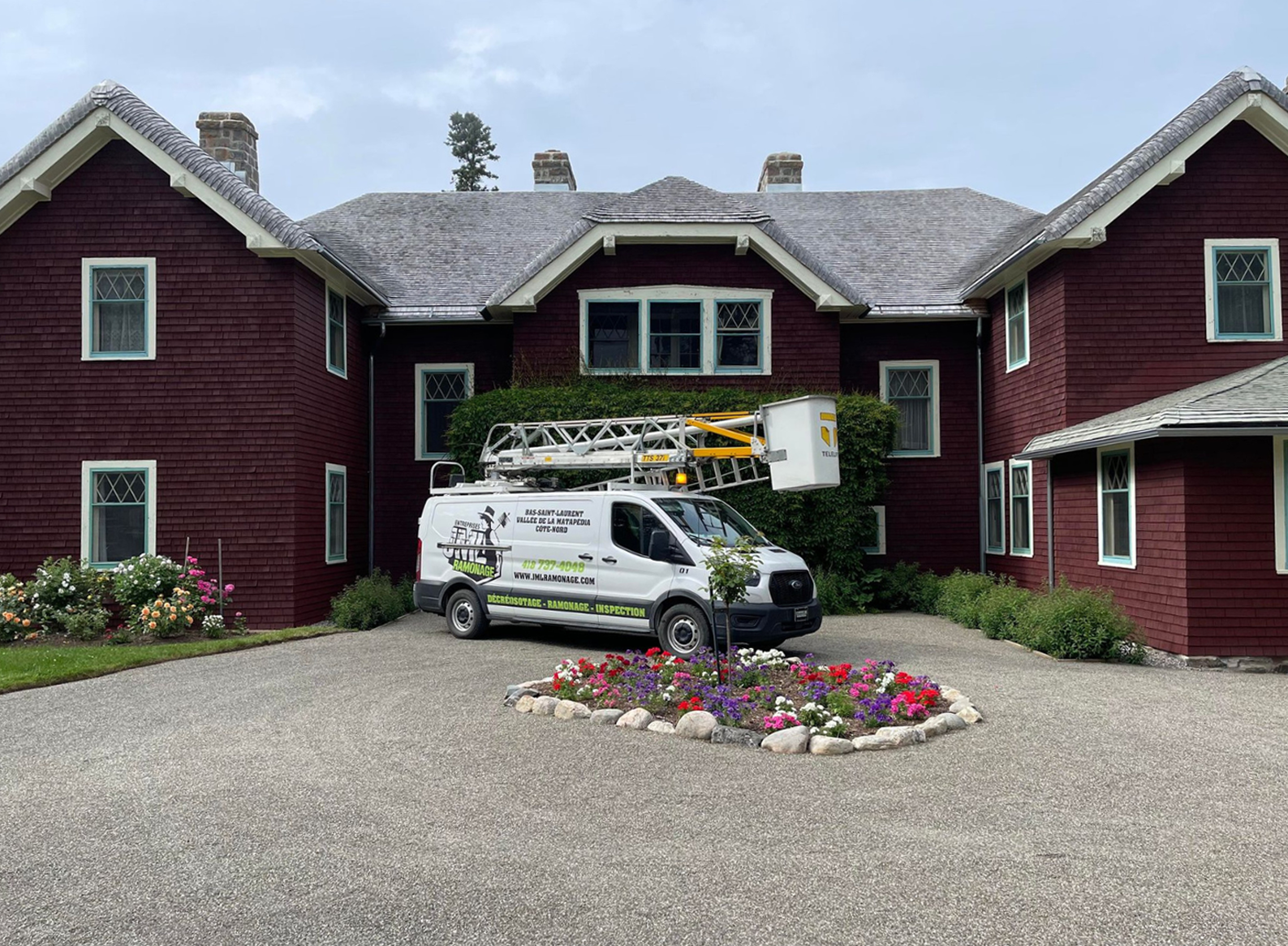 Une camionnette blanche est garée devant une grande maison rouge.