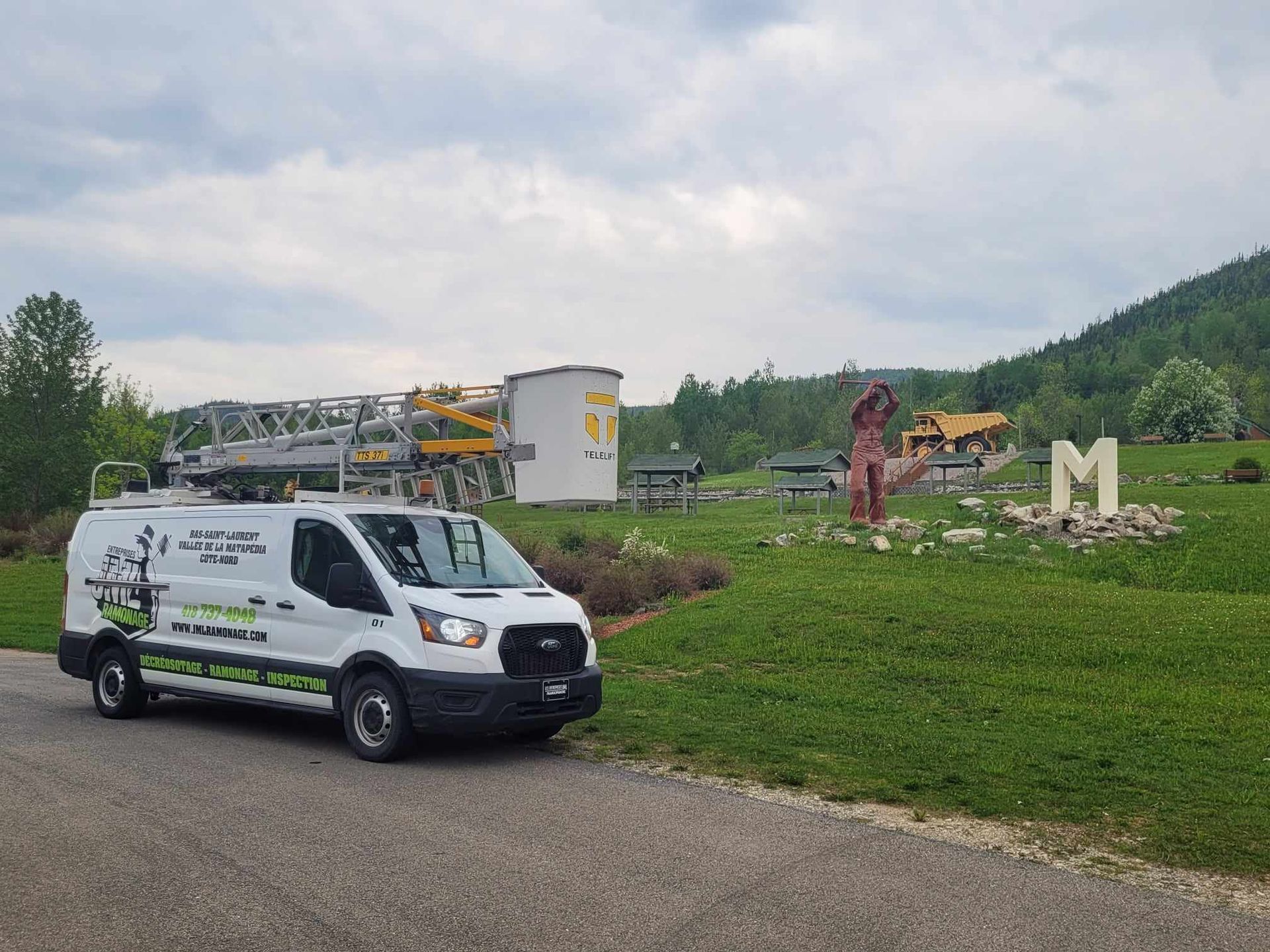 Une camionnette blanche est garée devant un champ herbeux.