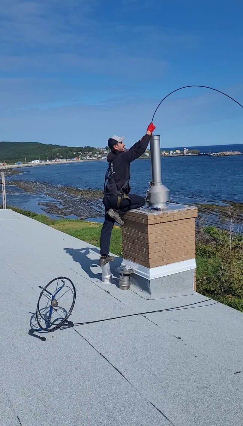Un homme nettoie une cheminée à côté de l'océan.